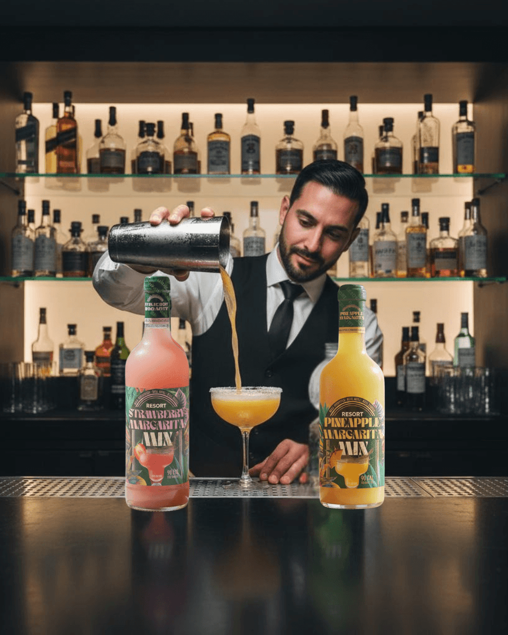 Barista pouring a drink from a cocktail shaker with Pineapple Margarita Mix bottles on a bar.