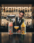 Barista pouring a drink from a cocktail shaker with Pineapple Margarita Mix bottles on a bar.